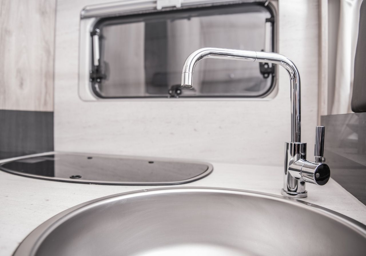 Mobile RV plumbing technician arriving at a residential driveway with service van